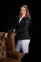 Woman in equestrian attire sitting on a brown leather chair against a black background