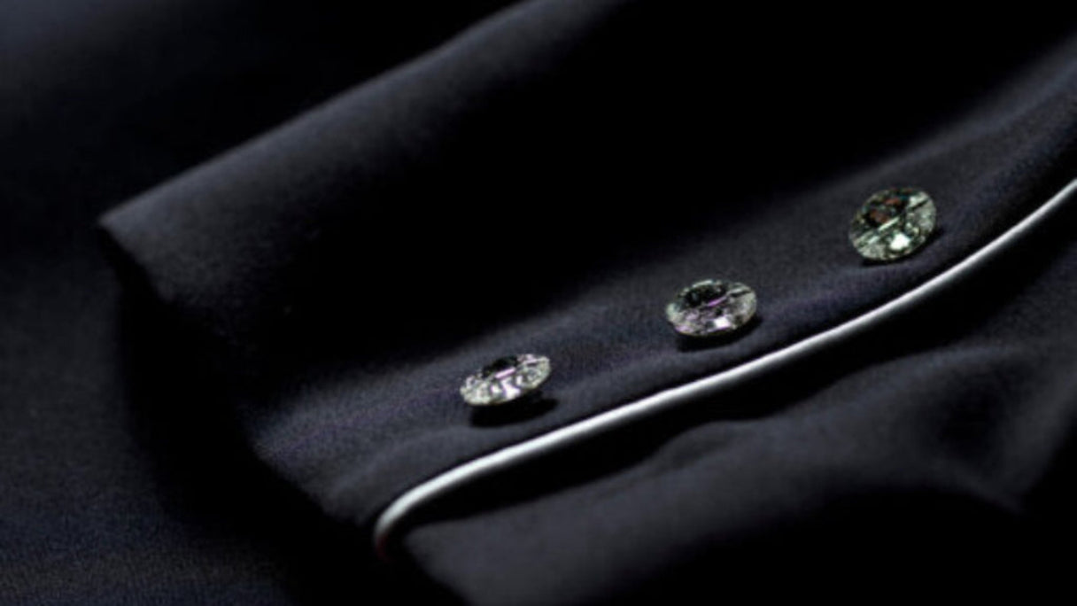 Close-up of a black garment with decorative buttons on a dark background
